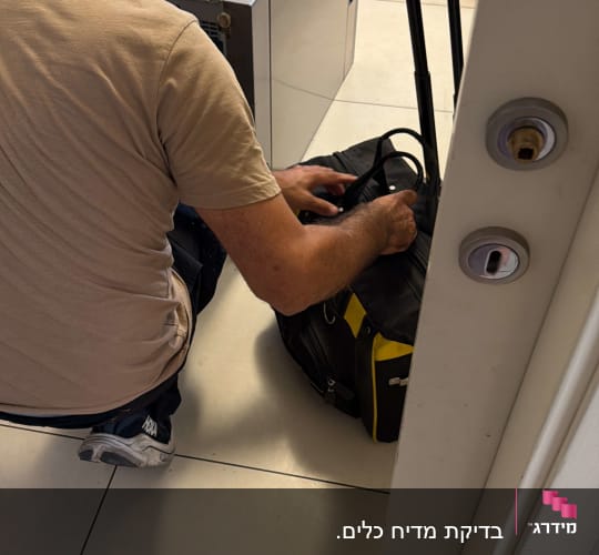 טכנאי מוצרי חשמל במהלך תיקון מדיח כלים במטבח